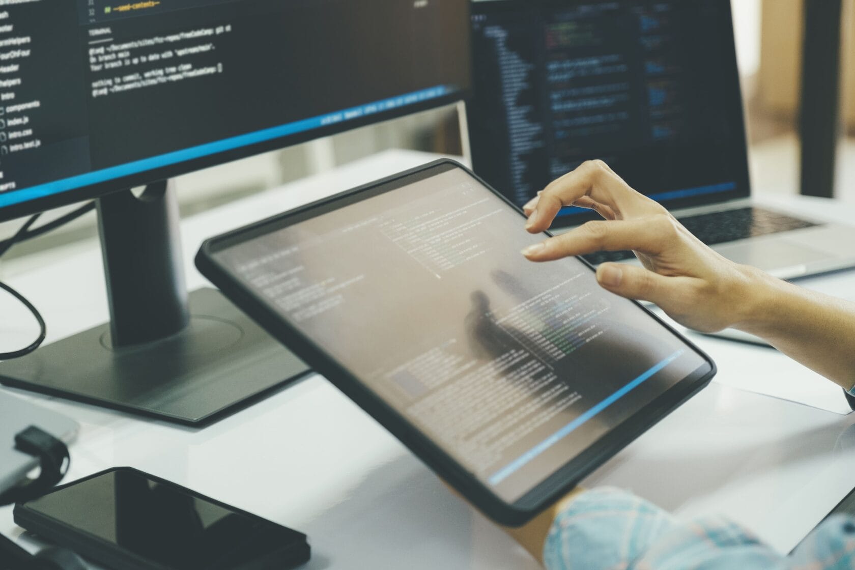 Software tester analysing program code on two screens
